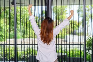 Woman stretching her arms while standing and looking sunrise thr